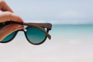 outdoor photo ocean with female hand foreground woman holding summer sunglasses sea